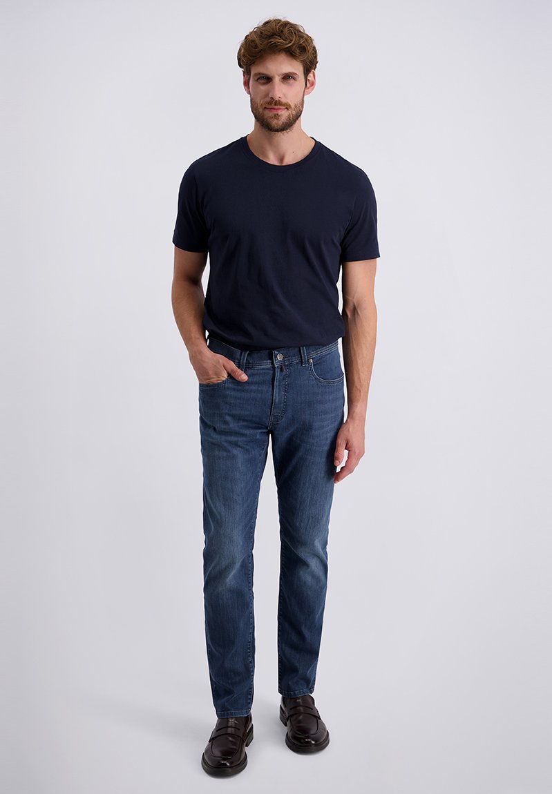 Marineblauw t-shirt gecombineerd met donkerblauwe spijkerbroek. Slim fit ontwerp, katoenen stof, subtiele textuur. Bruine schoenen met een gladde afwerking.