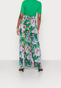 Un pantalon large à motifs floraux présente un imprimé vibrant de fleurs roses, orange et vert sur un fond bleu clair. Tissu lisse avec un design évasé.