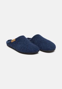 Un paio di pantofole in feltro blu scuro, con suole nere e un piccolo etichetta del marchio color beige sul lato, mostrato su uno sfondo bianco.