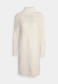 Abito in maglia di colore crema con collo alto, texture a coste, maniche lunghe e silhouette dritta. Presenta un orlo che termina sopra il ginocchio.
