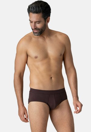 Caleçons bruns en coton avec une texture lisse et une taille élastique, présentant des coutures latérales et un design ajusté, modèle montré de côté.