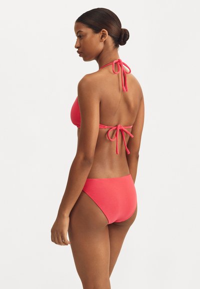 Bikini rose avec un design à col halter, des liens ajustables et une coupe de bas simple. Texture lisse avec un minimum de détails.