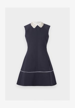 Φόρεμα χωρίς μανίκια σε ναυτικό μπλε χρώμα με φαρδιά φούστα, λευκό κολάρο τύπου Πίτερ Παν με διακόσμηση και λεπτό λευκό τελείωμα κοντά στη ραφή, σε ανοιχτό φόντο.