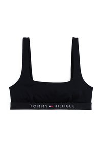 Črn krajši top bralette iz gladkega materiala z širokimi naramnicami in elastičnim trakom z logotipom, ki vsebuje "TOMMY HILFIGER" v beli in rdeči barvi.