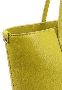 Geel leren handtas met een gestructureerde afwerking. Heeft een gestructureerde vorm, een dunne schouderband en zichtbare stiksels langs de randen.