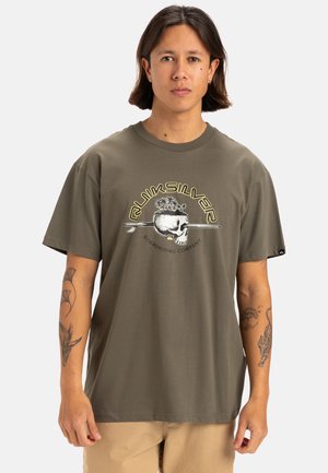 Camiseta de algodón verde oliva con un diseño gráfico de calavera rodeada de plantas, cuello redondo, mangas cortas y corte holgado.