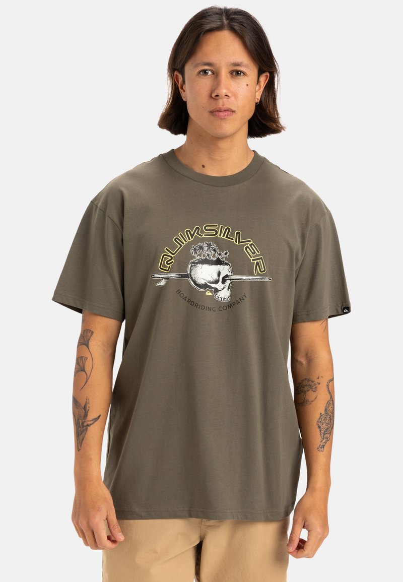 Camiseta de algodón verde oliva con un diseño gráfico de calavera rodeada de plantas, cuello redondo, mangas cortas y corte holgado.
