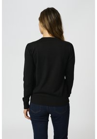 Maglione nero con maniche lunghe, polsini e orlo a coste, caratterizzato da un colletto rotondo. Il tessuto è liscio e aderente, con dettagli discreti sulle spalle.