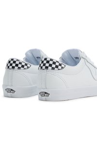 Baskets en cuir blanc avec un accent en damier au talon et un patch logo sur le côté. Texture lisse, forme arrondie et design à lacets.