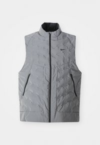 Chaleco gris acolchado con cuello alto, cremallera frontal y dos bolsillos laterales. Presenta una sutil textura acolchada y un pequeño logo negro en el pecho.
