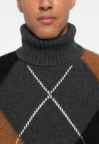 Γκρι πουλόβερ με ζιβάγκο και κλωστή καμπύλης, με μαύρες και καφέ λεπτομέρειες και λευκό διαμαντένιο μοτίβο στο στήθος.