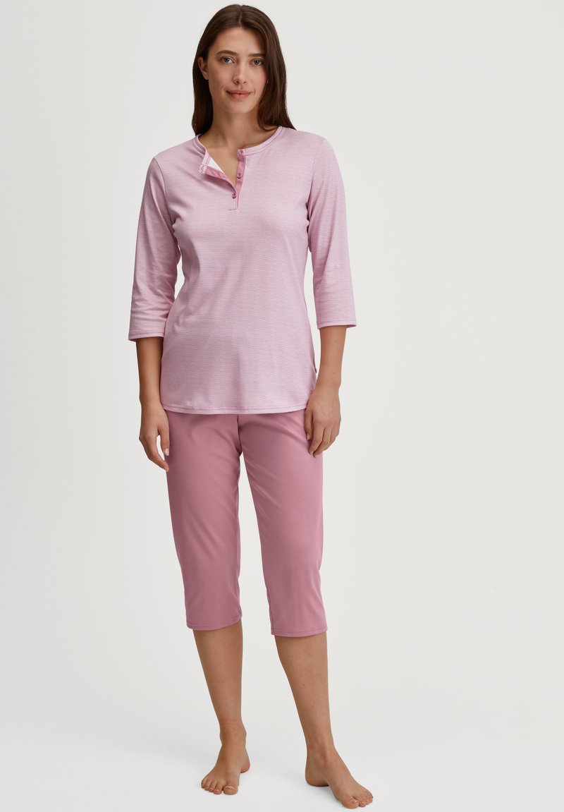 Roze katoenen pyjama set met een lange mouwen top met een henley hals en 3/4 mouwen, gecombineerd met knielange broek. Glad textuur.
