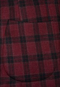 Czerwono-czarna kratka z wełny z dodatkiem kieszeni. Tekstura jest gładka i tkana, z białymi liniami siatkowymi przechodzącymi przez wzór.