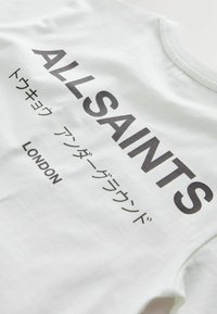 White cotton t-shirt featuring bold black text, "ALL SAINTS," with Japanese characters and "LONDON" below, round neck design, smooth texture.