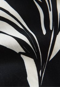 Tissu noir et blanc avec des rayures audacieuses, abstraites, semblables à celles d'une zèbre, et une texture tissée visible.