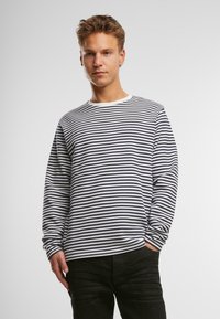 Stribet langærmet skjorte med marineblå og hvide vandrette striber, rund halsudskæring og løs pasform, parret med mørke bukser.