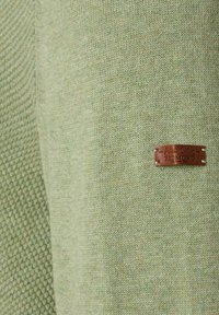 Zielony sweter z dzianiny z teksturalnym wzorem z jednej strony i gładkim materiałem z drugiej, z przyszytą brązową skórzaną metką marki.