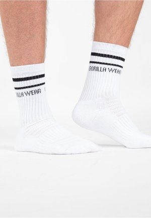 Witte sportkousen met ribbelstructuur, voorzien van zwarte strepen aan de bovenkant en "GORILLA WEAR" gedrukt aan de zijkant.