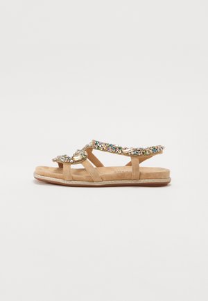 Sandales plates en daim beige avec plusieurs lanières. Décorées de strass multicolores et d'un accent métallique, elles disposent d'une semelle texturée.