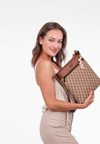 Hnědá vzorovaná kabelka s lesklým povrchem, která má akcent v podobě cik-cak a nastavitelné ramenní popruhy. Design je čtvercový s horním zipem.