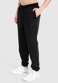 Sorte sweatpants lavet af bomuldsblanding, med elastisk talje med snørre, sidelommer og ribbede manchetter ved anklen.