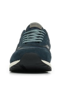 Marineblauwe suède sneaker met textuurstof, nettong en lichtblauwe veters. Heeft een contrasterende witte zool en een logo-accent op de tong.