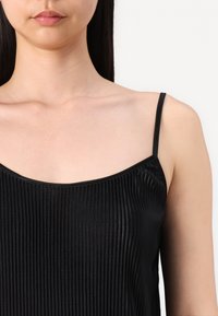 Top negro sin mangas con finos pliegues verticales, presenta un escote amplio y tirantes delgados. Textura suave y diseño ajustado.