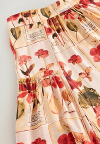 Abito con stampa floreale su uno sfondo pesca chiaro, decorato con fiori rossi e foglie verdi. Vita arricciata e tessuto morbido.