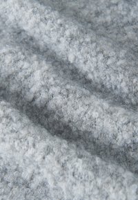 Lichtgrijs textiel met een getextureerd, pluizig oppervlak. Zacht en fuzzy uiterlijk, met subtiele variaties in kleur en textuur.