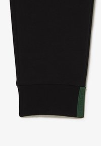 Zwarte sweatpants met ribgebreide boorden, voorzien van een textuur groene logo patch aan de onderkant. Gemaakt van een soepele, rekbare stof.
