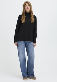 Fekete, hosszú ujjú, garbós pulóver, világoskék, bő szárú farmernadrággal és szürke, slip-on cipővel párosítva. Egyszerű, hétköznapi outfit, puha textúrákkal.