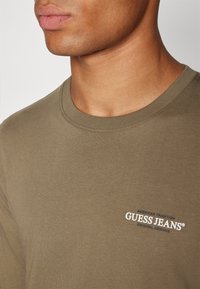 Guess Jeans AMERICAN - Ilgarankovis viršutinės dalies drabužis - olive light green