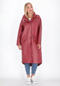 Vattentålig lång kappa i vinröd, med huva, tryckknappar, stora framfickor och en något längre bakre fåll.
