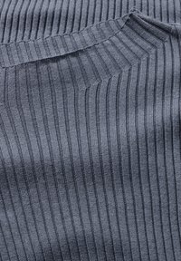 Tissu tricoté côtelé gris plié avec des coutures diagonales et des lignes de texture verticales remplissant le cadre.