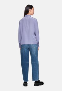 Light purple blouse with a collared neckline, long sleeves; paired with loose blue jeans featuring stitching details and a relaxed fit.