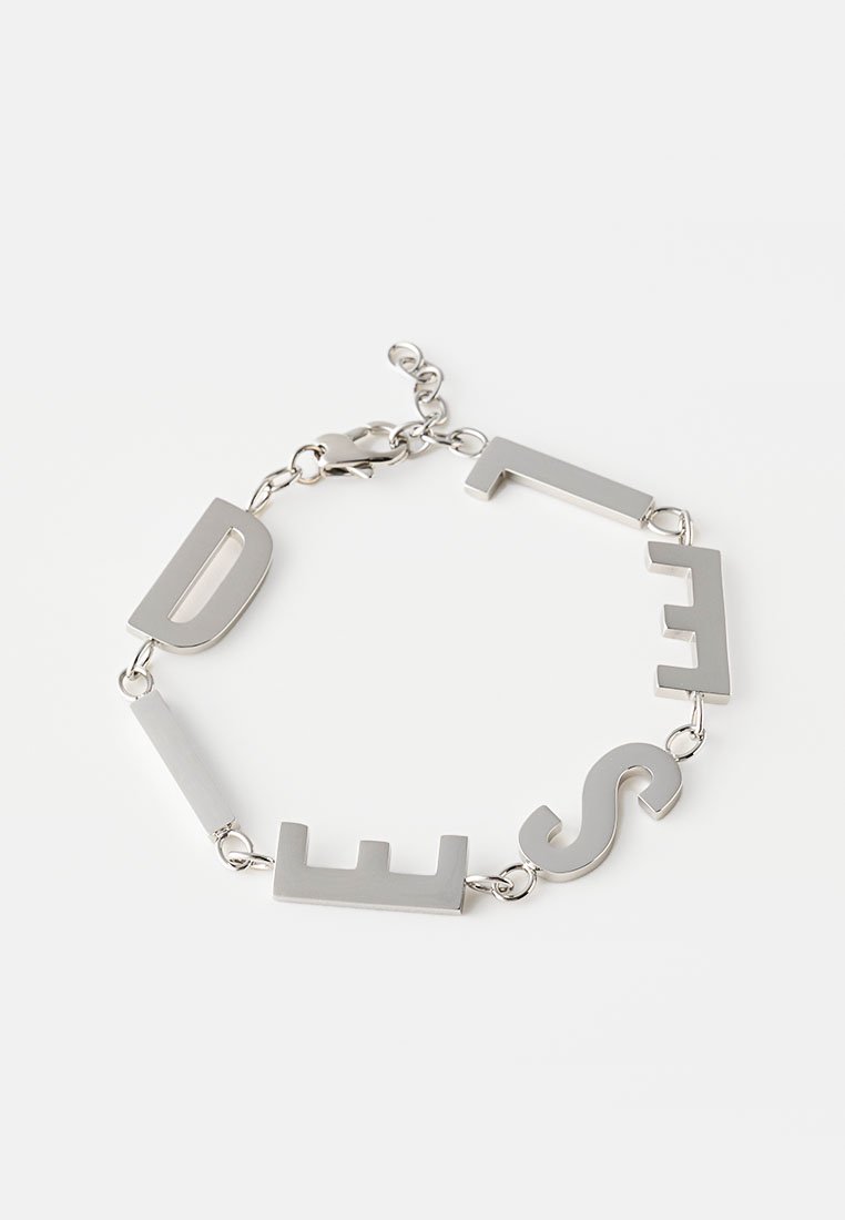 Silbernes Metallarmband mit fettgedruckten, großgeschriebenen Buchstaben. Die Glieder wechseln sich zwischen soliden Rechtecken und Buchstaben ab und sind mit einem Karabinerverschluss versehen.