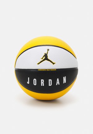 Un ballon de basket jaune, blanc et noir avec une surface en caoutchouc texturé, la marque "JORDAN" et un logo en silhouette sur la partie supérieure.