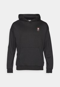 Felpa nera con cappuccio realizzata in tessuto morbido, dotata di una tasca a marsupio frontale, polsini a coste e una piccola patch con logo in alto a sinistra.