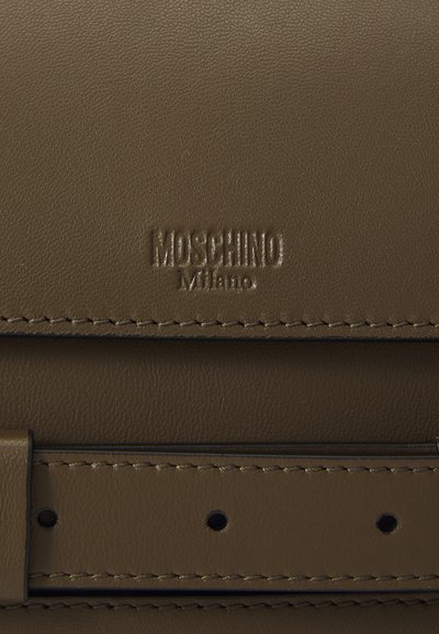 Hnědá kožená taška s vyraženým logem "Moschino Milano". Má hladký povrch, čisté linie a viditelné detaily šití.