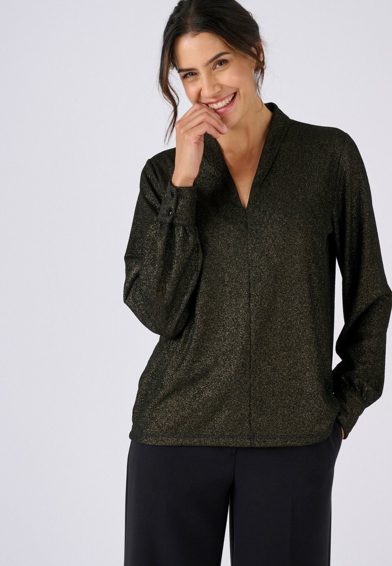 Blusa negra brillante con cuello en V y mangas largas, con puños abotonados y un ajuste holgado, creando una apariencia texturizada y elegante.