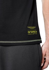 Czarny bawełniany t-shirt z żółtymi logo: "Aston Martin" i "aramco Formula One Team". Ma okrągły dekolt i kontrastowe szwy.