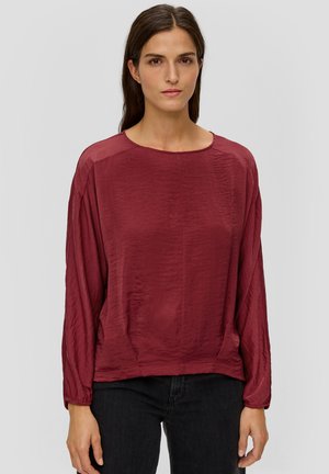 Bordeaux lange mouwen blouse met een ronde hals, gemaakt van een gladde stof. Heeft een relaxte pasvorm en licht geraffineerde mouwen voor extra textuur.