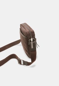 Brown fabric shoulder bag with a zip closure, flat rectangular shape, contrasting grey accents, and an adjustable strap with metal hardware.