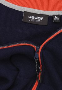 Marineblauwe pullover met oranje en grijze strepen, ritssluiting en een zachte textuur. Etiket zegt "J&JOY," maat L. Voorzien van een ritstrekkertje met zwarte accenten.
