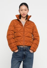 Brun quiltet pufferjakke med høj krave, lynlåslukning og cropped design; har et geometrisk diamantmønster og glat tekstur.