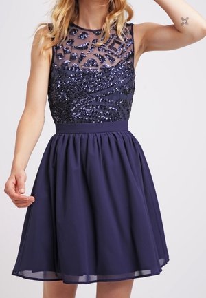 Navy dress with a fitted sequined bodice and sheer neckline, transitioning to a full skirt. Textured detailing and sleeveless design are notable.