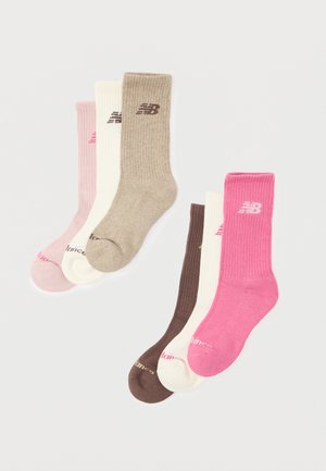 Seks par ribbestrikkede crew-sokker i nyanser av rosa, beige, hvit og brun, hver med New Balance-logoen nær toppen.