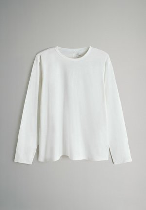 Hvid langærmet t-shirt lavet af blødt, letvægtsstof med rund halsudskæring og lige snit. Glat tekstur, minimalistisk design.