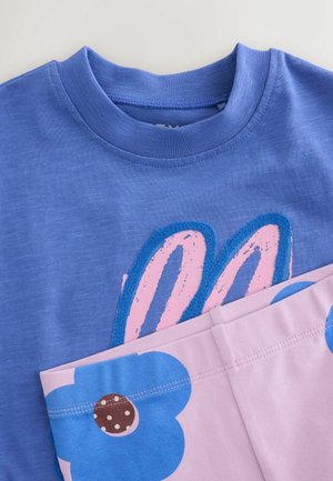 Blå kortærmet skjorte med pinke og blå kaninører design kombineret med lyserøde bukser med store blå blomsterprint.