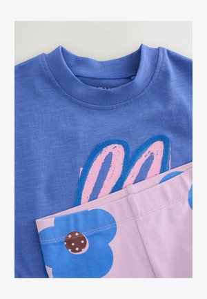 Modra majica s kratkimi rokavi z roza in modrimi zajčjimi ušesi ter svetlo roza hlače z velikimi modrimi cvetnimi potiski.